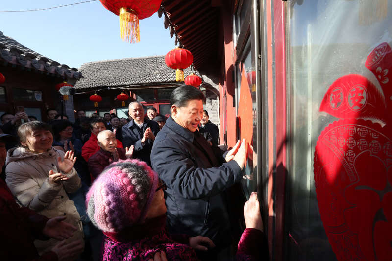 2019年2月1日上午，習近平在北京前門東區(qū)草廠四條胡同32號院，高興地拿起一幅“?！弊?，親自貼到門上，給這里的老街坊們拜年。新華社記者 鞠鵬 攝
